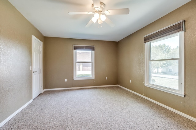 spare room featuring baseboards, a ceiling fan, carpet, and a textured wall