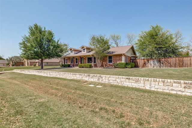 ranch-style home featuring brick siding, a front lawn, and fence