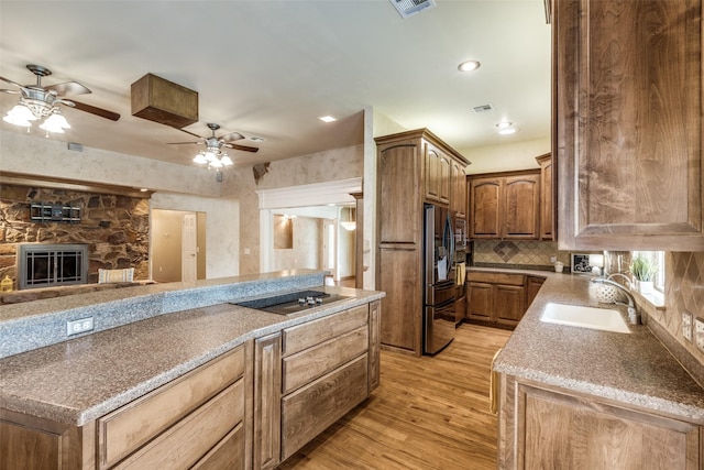 kitchen featuring a sink, black electric cooktop, ceiling fan, stainless steel refrigerator with ice dispenser, and light wood-style flooring