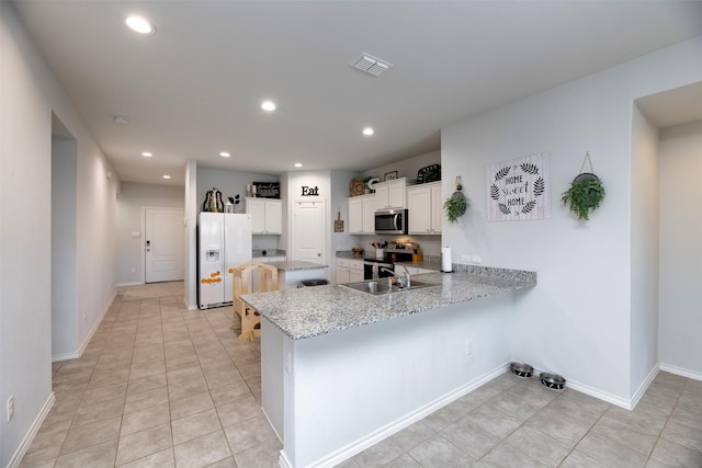 9449 Firedog Dr, Fort Worth, TX 76131 - kitchen with appliances with stainless steel finishes, a peninsula, recessed lighting, white cabinets, and light stone counters