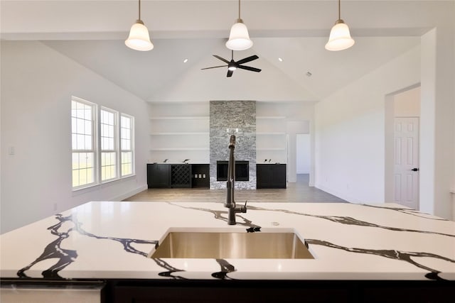 kitchen with a ceiling fan, built in features, a fireplace, and pendant lighting