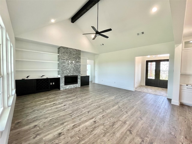 unfurnished living room featuring light wood finished floors, beam ceiling, visible vents, ceiling fan, and high vaulted ceiling