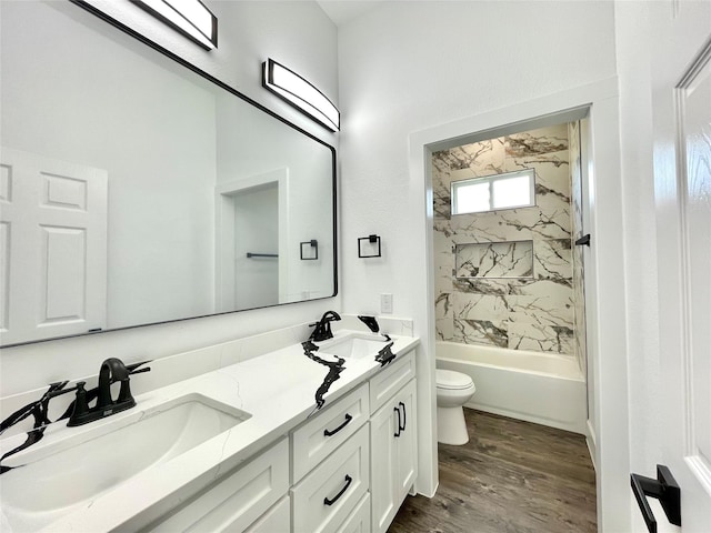full bath with double vanity, wood finished floors, toilet, a sink, and shower / bathing tub combination