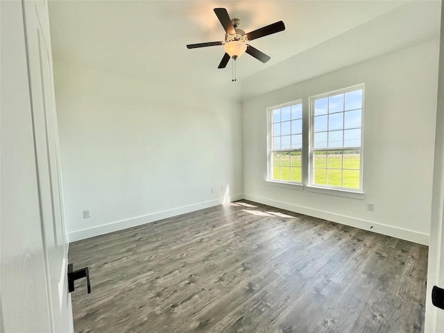 empty room with dark wood-type flooring, a ceiling fan, and baseboards