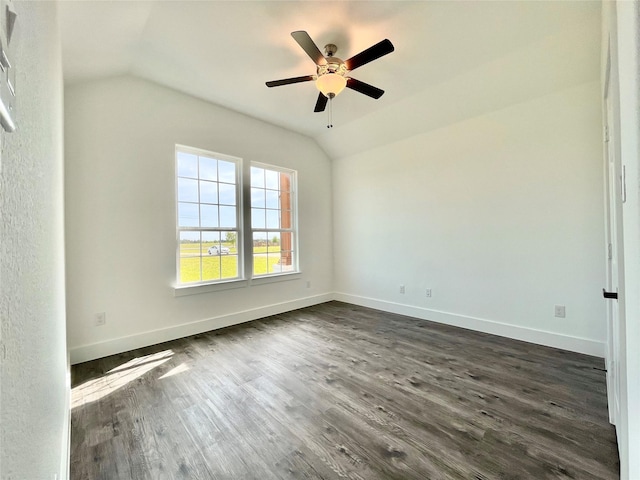 empty room featuring dark wood finished floors, vaulted ceiling, baseboards, and ceiling fan