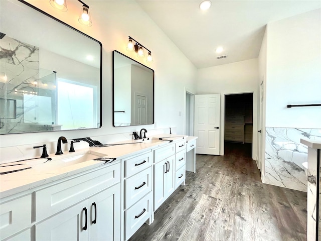 bathroom with double vanity, wood finished floors, a marble finish shower, and a sink