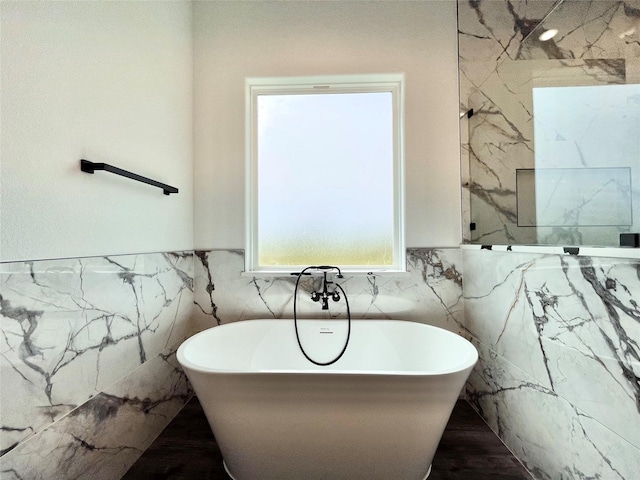full bath featuring tile walls, a wainscoted wall, and a freestanding tub