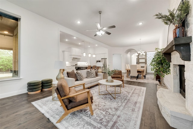 living area featuring baseboards, a wealth of natural light, ceiling fan with notable chandelier, and wood finished floors