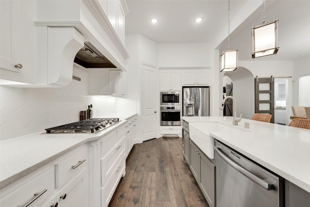 kitchen with appliances with stainless steel finishes, a sink, light countertops, gray cabinetry, and dark wood-style floors