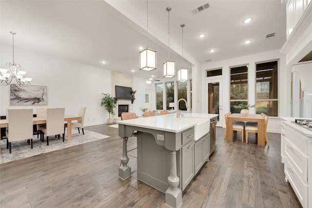 kitchen with visible vents, light countertops, a large fireplace, a sink, and gray cabinetry