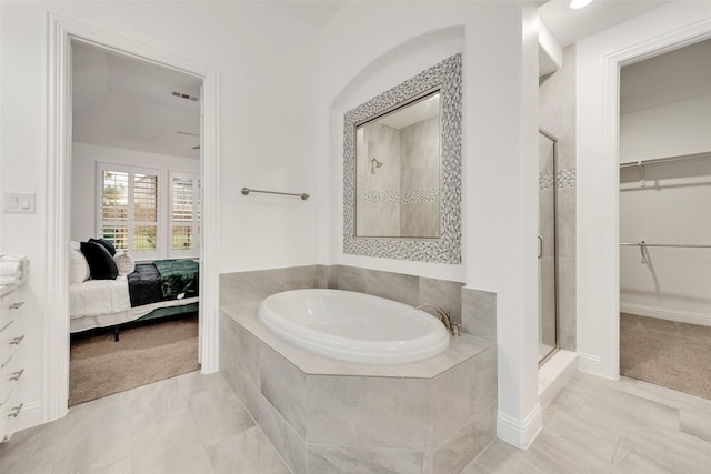 ensuite bathroom featuring a garden tub, a walk in closet, ensuite bathroom, and a shower stall