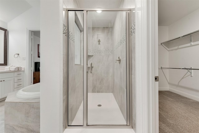 full bath featuring vanity, a walk in closet, a garden tub, and a stall shower