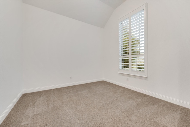 carpeted spare room featuring baseboards and lofted ceiling