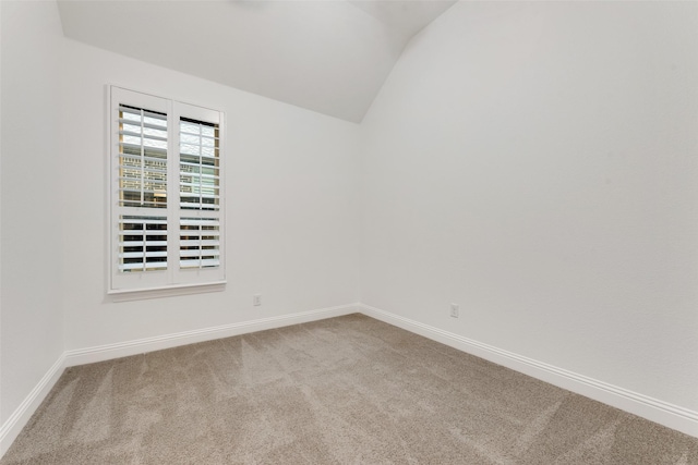 carpeted spare room with baseboards and lofted ceiling