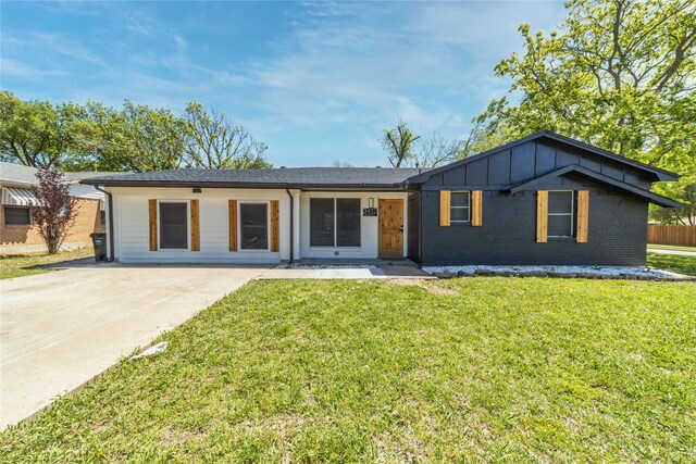 ranch-style home featuring a front lawn, driveway, brick siding, and board and batten siding