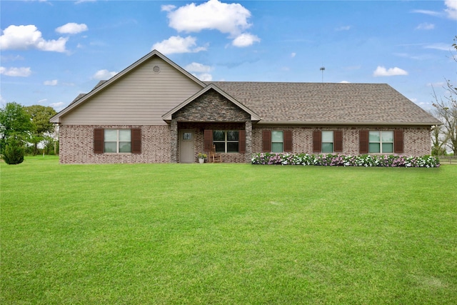 single story home featuring brick siding, a front yard, and roof with shingles