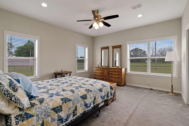 carpeted bedroom with visible vents, multiple windows, and baseboards