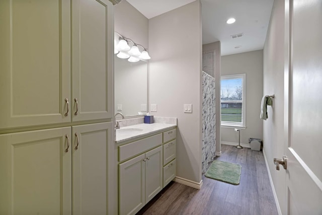 bathroom with vanity, curtained shower, visible vents, baseboards, and wood finished floors