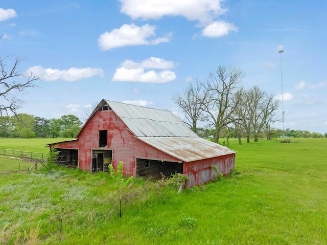 view of barn with fence and a lawn
