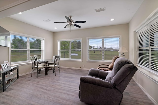 living room featuring wood finished floors, a ceiling fan, visible vents, and baseboards