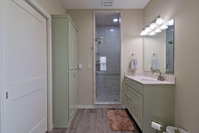 full bathroom with wood finished floors, a shower stall, vanity, baseboards, and visible vents