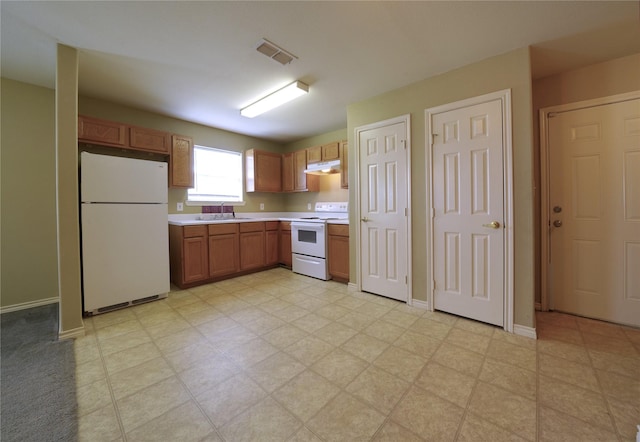 kitchen with white appliances, light countertops, under cabinet range hood, visible vents, and a sink