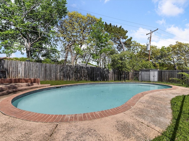 view of pool featuring a fenced backyard, a fenced in pool, an outdoor structure, and a storage unit