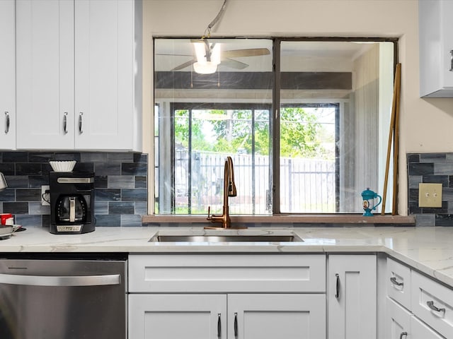 kitchen featuring white cabinetry, stainless steel dishwasher, decorative backsplash, and a sink