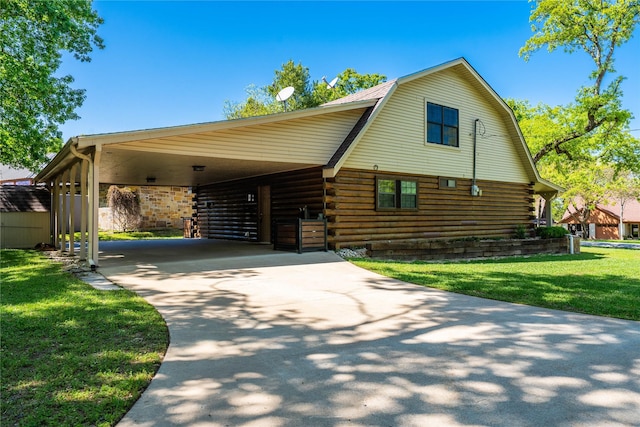 view of front of property with concrete driveway, log siding, an attached carport, a front yard, and a gambrel roof