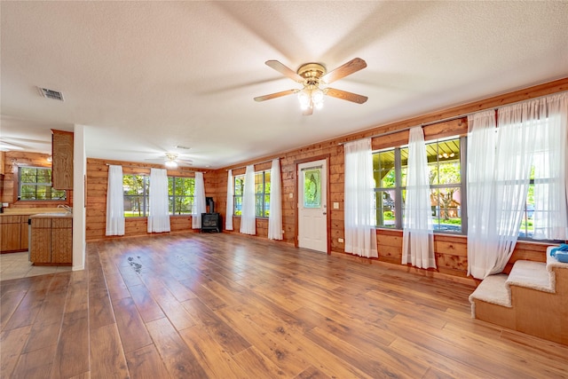 unfurnished living room with visible vents, a ceiling fan, and a textured ceiling