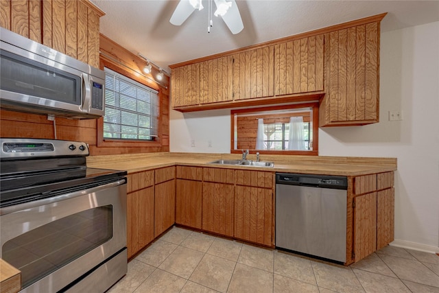 kitchen featuring appliances with stainless steel finishes, light tile patterned flooring, a sink, and a wealth of natural light