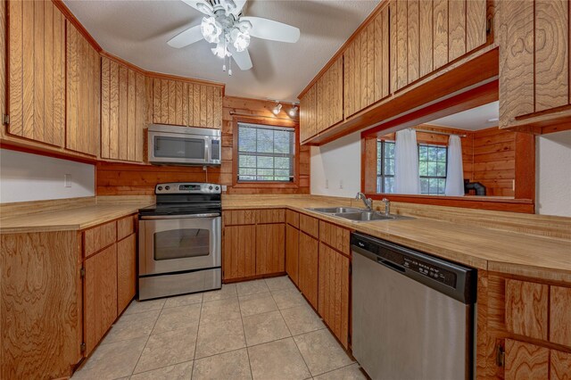 kitchen with plenty of natural light, light tile patterned floors, a sink, and appliances with stainless steel finishes
