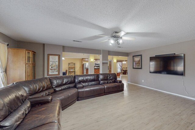 8202 Silverton Dr, Arlington, TX 76001 - living area with baseboards, a ceiling fan, light wood-style floors, and a textured ceiling