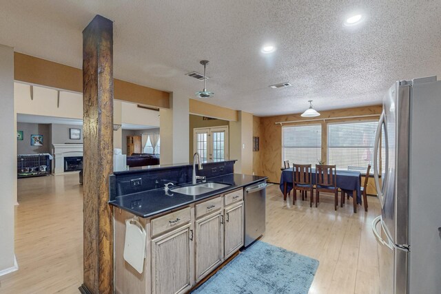 8202 Silverton Dr, Arlington, TX 76001 - kitchen with a sink, light wood-type flooring, appliances with stainless steel finishes, dark countertops, and a textured ceiling
