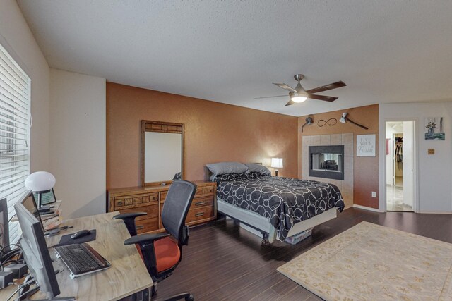 8202 Silverton Dr, Arlington, TX 76001 - bedroom with dark wood-type flooring, a ceiling fan, a tile fireplace, and a textured ceiling