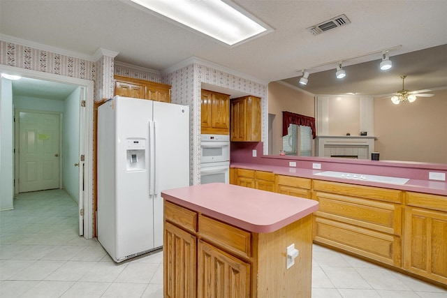kitchen featuring a center island, visible vents, a ceiling fan, white appliances, and light tile patterned floors