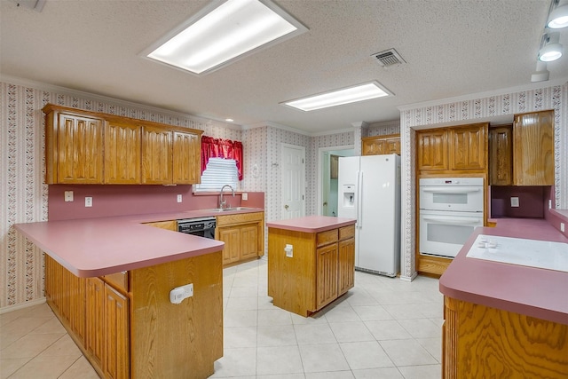 kitchen featuring a peninsula, a sink, wallpapered walls, white appliances, and crown molding