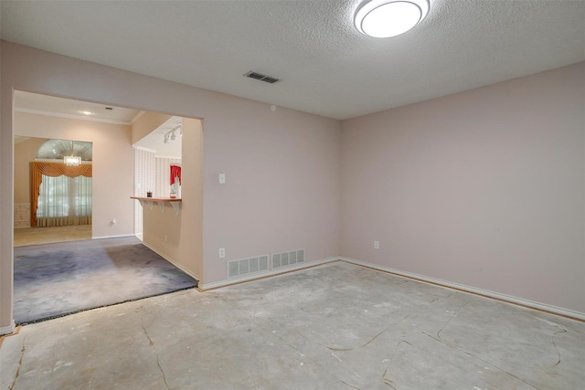 empty room with concrete flooring, baseboards, a textured ceiling, and visible vents
