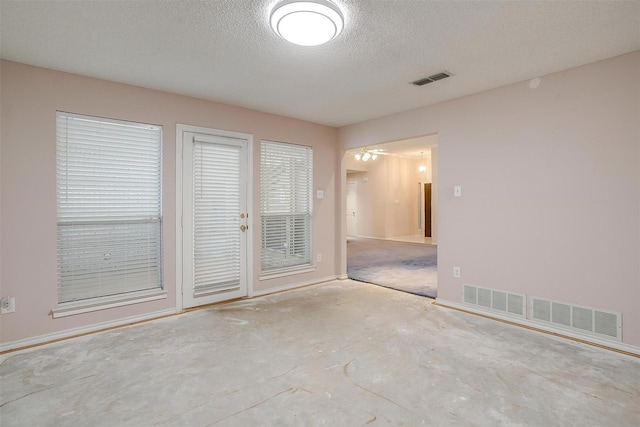 spare room featuring baseboards, a textured ceiling, and visible vents