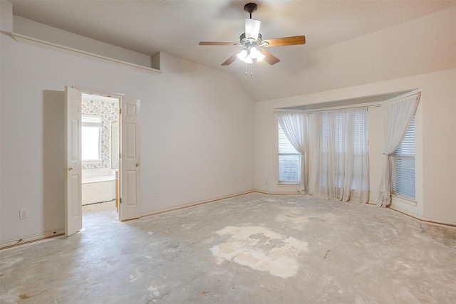 spare room featuring vaulted ceiling, unfinished concrete flooring, a ceiling fan, and a healthy amount of sunlight