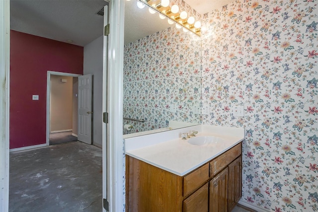 bathroom with concrete flooring, wallpapered walls, vanity, and baseboards