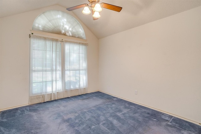 spare room with dark carpet, vaulted ceiling, and a ceiling fan