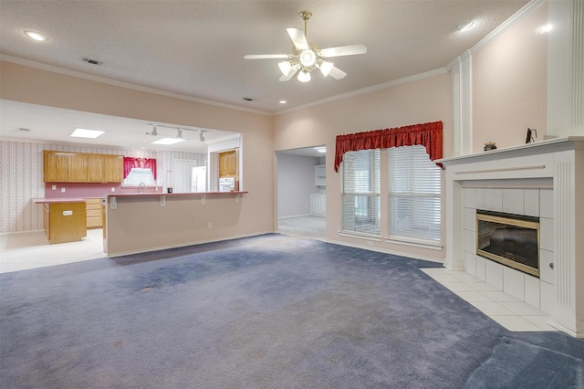 unfurnished living room featuring baseboards, light colored carpet, ceiling fan, a fireplace, and ornamental molding
