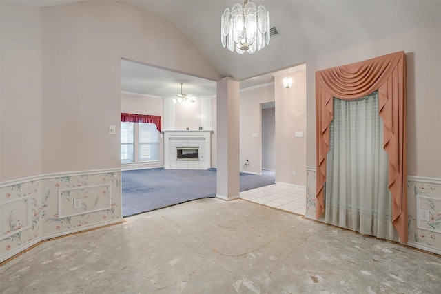 unfurnished living room with lofted ceiling, a tiled fireplace, and an inviting chandelier