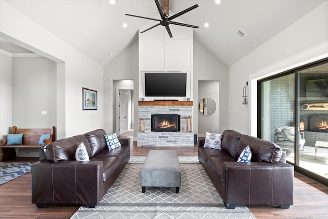 living area featuring high vaulted ceiling, wood finished floors, and a lit fireplace