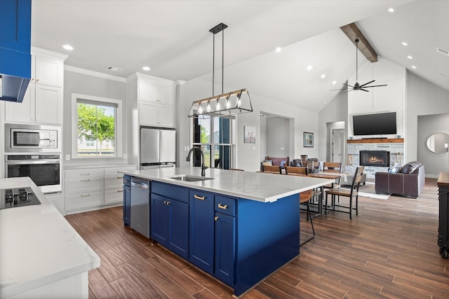 kitchen featuring blue cabinetry, a warm lit fireplace, stainless steel appliances, white cabinets, and a sink