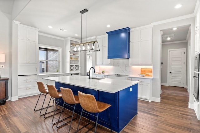 kitchen featuring wood finished floors, crown molding, a kitchen bar, and a sink