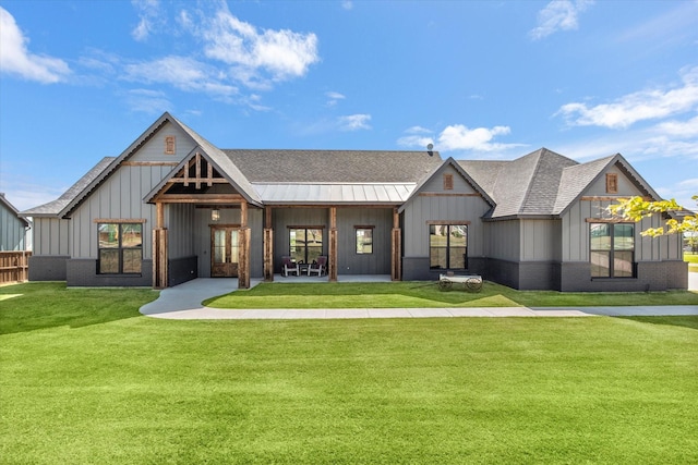 view of front of home with a front yard, a patio, a shingled roof, and board and batten siding
