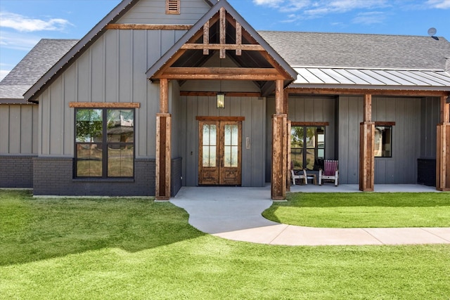 property entrance with a yard, a shingled roof, and board and batten siding