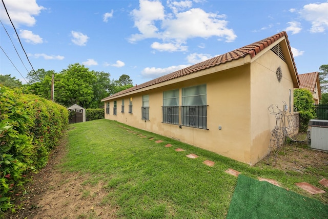 1803 Michael Ct, Arlington, TX 76010 - view of property exterior with stucco siding, a tiled roof, a yard, a storage unit, and cooling unit